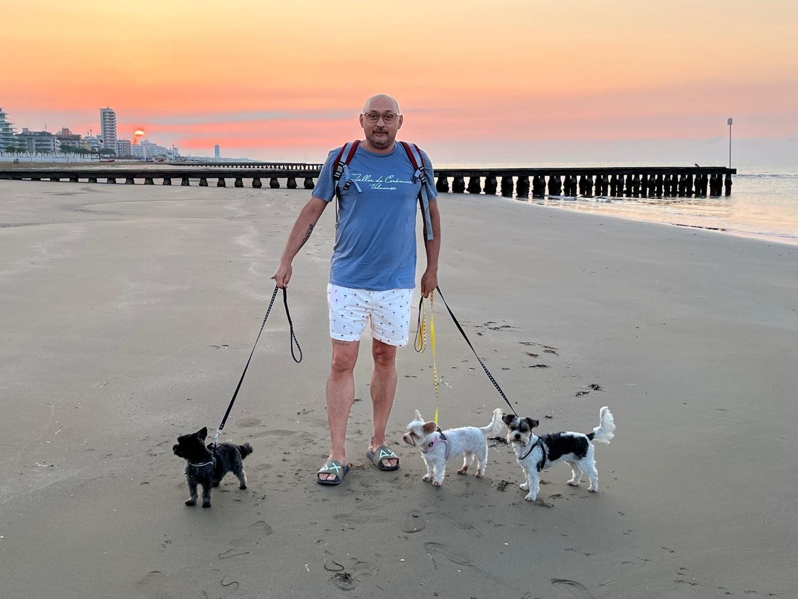 Luigi Migliozzi con tre piccoli cani sulla spiaggia al tramonto